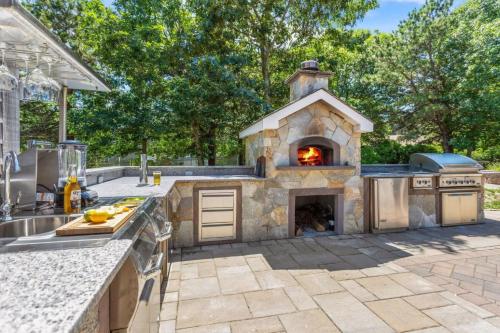 una cocina al aire libre con horno de pizza en un patio en Outdoor entertaining re-imagined Enjoy a new luxury back yard, en Eastham