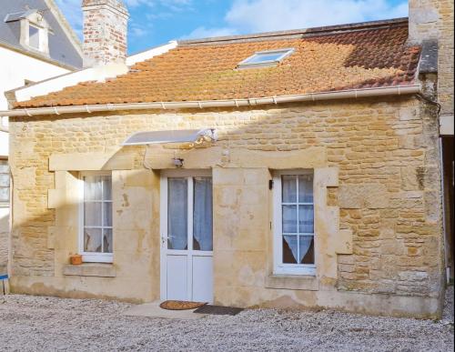 an old stone house with a dog sitting on the door at LaMaisonnette 500m plage Juno Beach in Bernières-sur-Mer