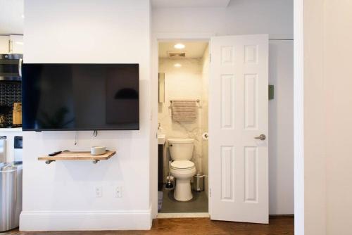 a bathroom with a toilet and a tv on a wall at 69-5A Modern Lower East Side 1BR Apt BRAND NEW in New York