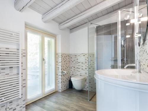 y baño con bañera, aseo y lavamanos. en Delfi - amazing design apartment with Lake view, en Parzanica