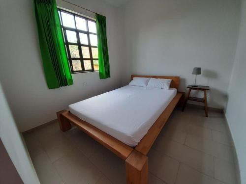 塔拉波托的住宿－BUNGAVILLA House Tarapoto，一张位于带绿色窗户的房间内的床铺