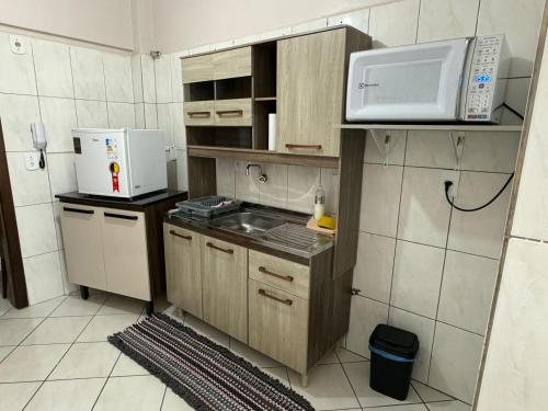 eine kleine Küche mit einer Spüle und einer Mikrowelle in der Unterkunft Apartamento com mobília nova 201! in Francisco Beltrão