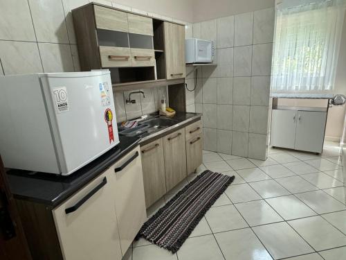 a small kitchen with a refrigerator and a sink at Apartamento com mobília nova 201! in Francisco Beltrão
