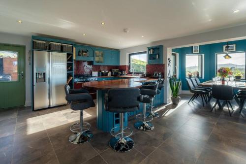 a kitchen with blue walls and a bar with stools at Blasket View - 5 Star in Dingle