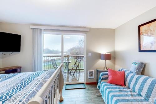 - une chambre avec un lit, un canapé et un balcon dans l'établissement Breakwater Inn - Mastodon Cottage #G, à Grayland