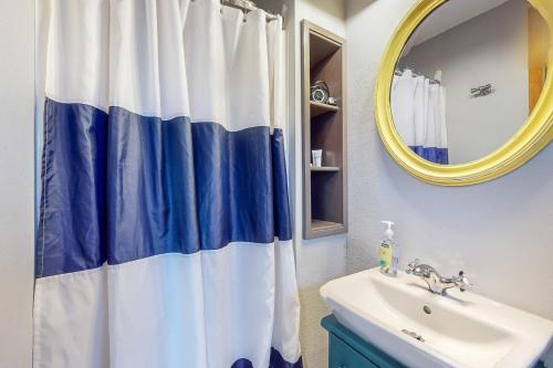 baño con cortina de ducha azul y blanco y lavamanos en Breakwater Inn - Mastodon Cottage #G, en Grayland