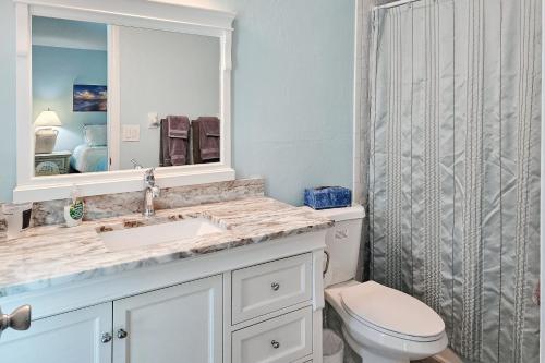 a bathroom with a sink and a toilet and a mirror at Away from it All Abode in Sanibel