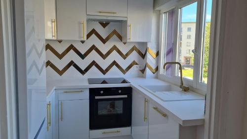 cocina con armarios blancos, fregadero y horno en Appartement Cosy tout confort - Brest en Brest