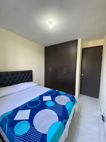 a bedroom with a bed with a blue blanket on it at Apartamento de Lujo Conjunto Marsella Real in Valledupar