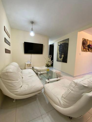 a living room with two white chairs and a tv at Apartamento de Lujo Conjunto Marsella Real in Valledupar