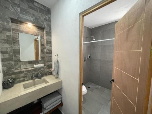 een badkamer met een wastafel, een toilet en een spiegel bij Casa OM in El Cuyo