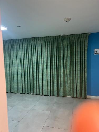 a room with green curtains in a room with a tile floor at Cozy Beachfront View in Portmore