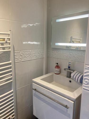 a white bathroom with a sink and a mirror at Mariners Corner in Bexhill