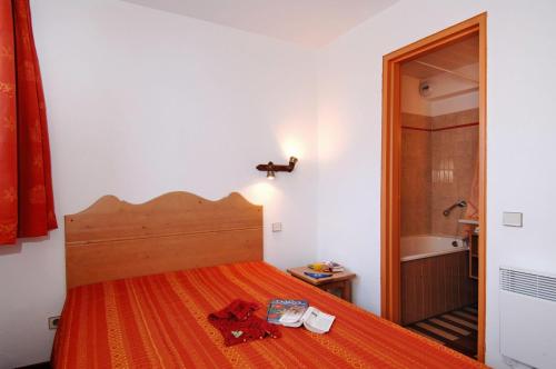 - une chambre avec un lit doté d'un couvre-lit orange dans l'établissement Résidence Odalys Le Hameau du Borsat, à Tignes