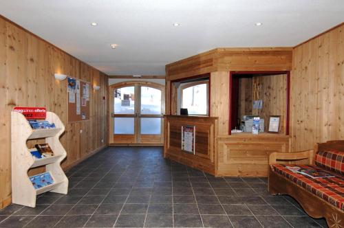Cette chambre dispose de murs en bois, d'un canapé et d'une étagère. dans l'établissement Résidence Odalys Le Hameau du Borsat, à Tignes