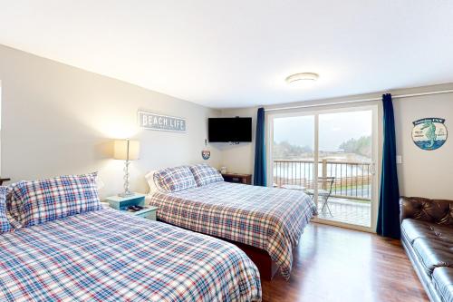 a bedroom with two beds and a couch and a balcony at Breakwater Inn - Josie Dyas Cottage #H in Grayland