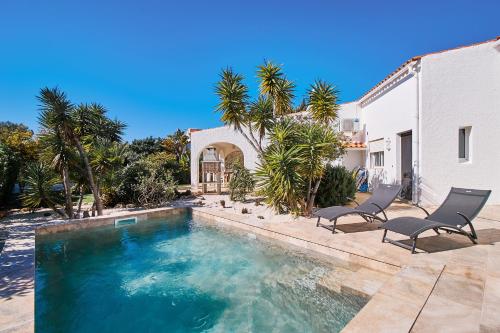 a swimming pool with two chairs and a house at Do Jardim in Carvoeiro