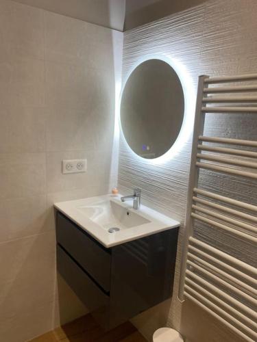 La salle de bains est pourvue d'un lavabo et d'un miroir rond. dans l'établissement Gîte avec Jacuzzi Un air de Provence, à Eyguières