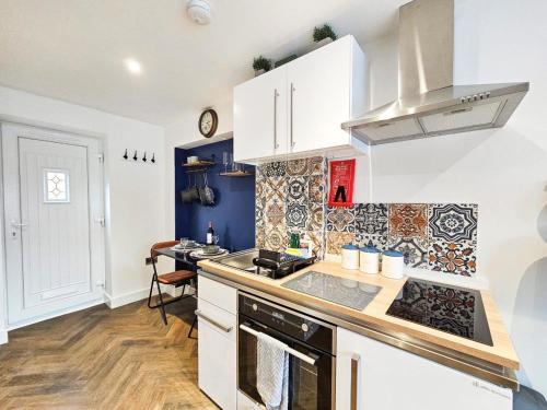 a kitchen with white cabinets and a stove top oven at Cobblestone Studio by Fortuna Property Portfolio in Cheltenham
