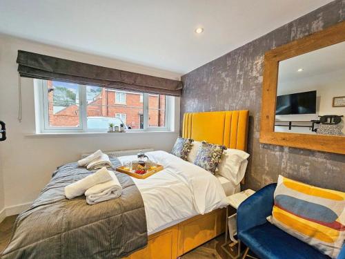 1 dormitorio con cama, espejo y silla en Cobblestone Studio en Cheltenham