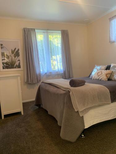 a bedroom with a bed and a window at The Homestead - cosy 3 bedroom house in Rotorua