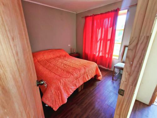ein Schlafzimmer mit einem Bett mit einer roten Bettdecke und einem Fenster in der Unterkunft Cabaña en campo in Parral