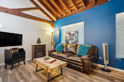 a living room with a leather couch and a tv at THE CARRICK in Bisbee