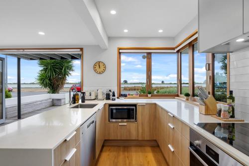 a large kitchen with white countertops and windows at Beachside Bliss - Redcliffs in Christchurch