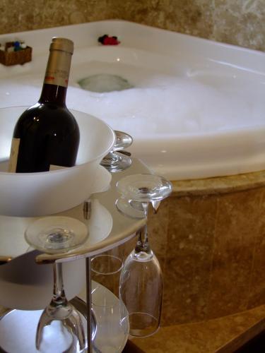 a bottle of wine on a shelf next to a bath tub at Pousada Ouro de Minas in Tiradentes
