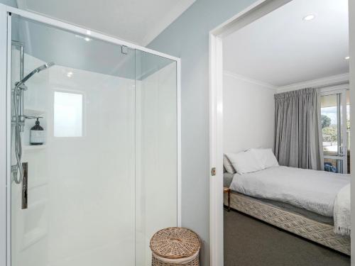 a bedroom with a glass door leading to a bed at Family Oasis - Pauanui Holiday Home in Pauanui