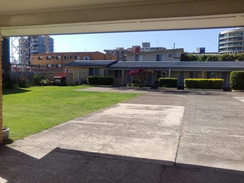 an empty patio with a yard with buildings at Forster and Wallis Lake Motel in Forster