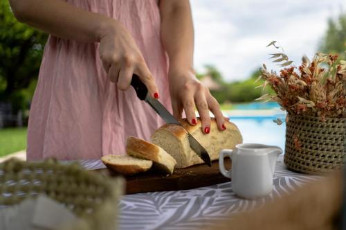 ラス・ラボナスにあるCabañas Ocho Solesのテーブルの上でナイフでパンを切っている女性