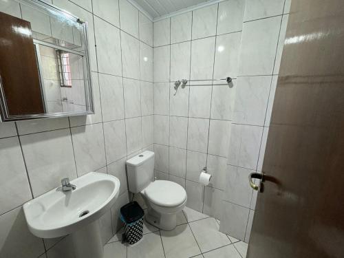 a white bathroom with a toilet and a sink at Apartamento com mobília nova 301 in Francisco Beltrão