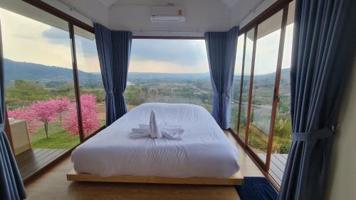 a bed in a room with a large window at Sirine​ Onsen​ รีสอร์ทออนเซนวิวทะเลหมอก in Khao Kho