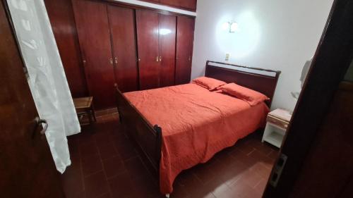 1 dormitorio con 1 cama con colcha de color naranja en Completa y Comoda Casa 4 Personas en Salta