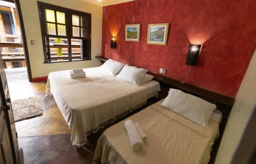 a bedroom with two beds and a red wall at Casario 1915 Pousada in Morretes