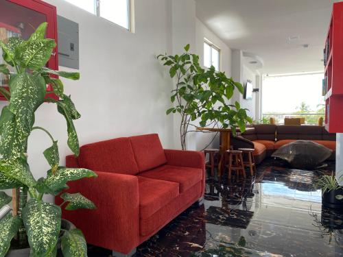 a living room with a red couch and some plants at Patty House Galapagos in Puerto Ayora