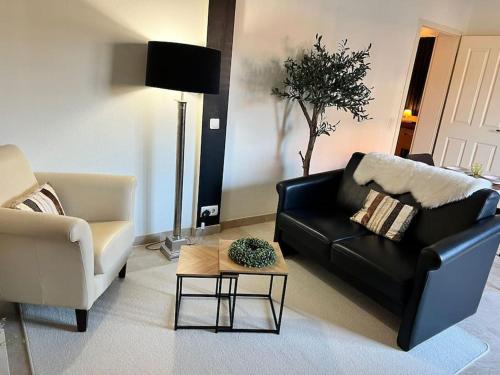 a living room with a black couch and a coffee table at Privatunterkunft in Gronau in Spechtholzhock