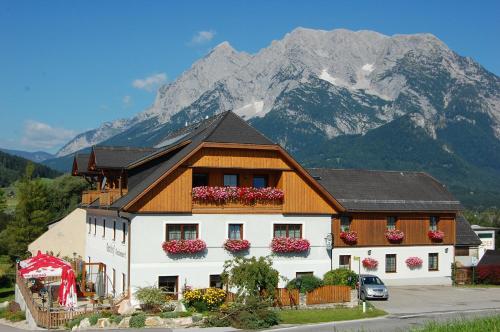 a building with flowers on the windows and a mountain at Gasthof Grabenwirt in Irdning