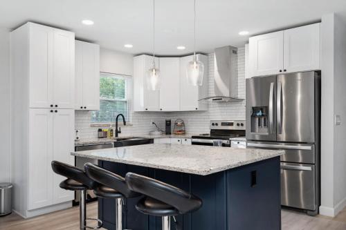 a kitchen with white cabinets and a large island with black bar stools at Catchy Relax Bradenton Beauty mins to Beaches in Bradenton