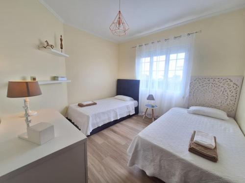 a bedroom with two beds and a table with a lamp at Garden House in São Vicente Ferreira