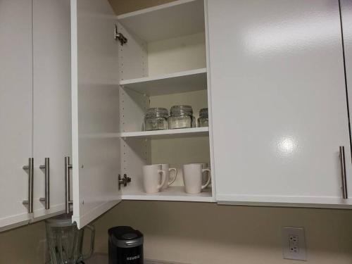 a kitchen with white cabinets with mugs in it at A Touch of Sunshine Ideal For Long Term Stays in Fayetteville