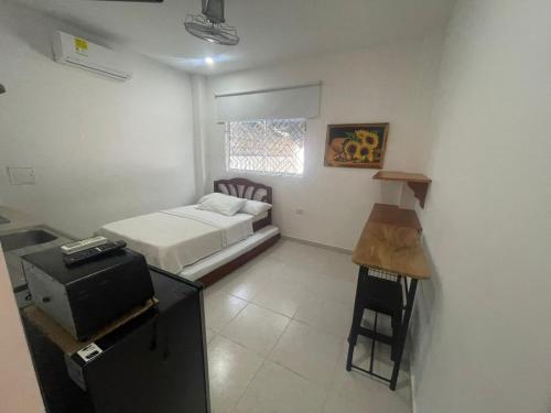 een kleine kamer met een bed en een bureau. bij Apartaestudio Playa Linda 101 in Coveñas