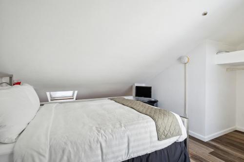 a white bedroom with a bed and a clock on the wall at THE CARRICK in Bisbee