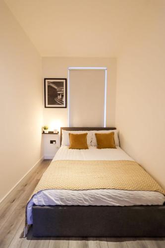 a bedroom with a large bed with yellow pillows at City Centre Hub Stirling, On Street Parking. in Stirling