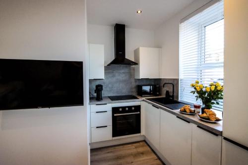 a kitchen with white cabinets and a black appliance at City Centre Hub Stirling, On Street Parking. in Stirling