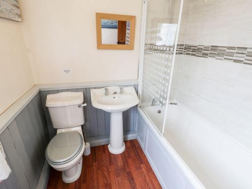 uma casa de banho com um WC, um lavatório e um chuveiro em Woodlands Cottage em Scarborough