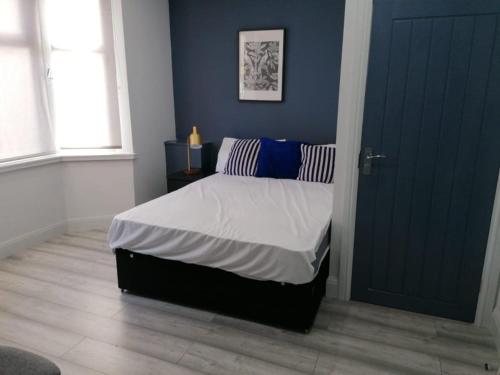 Everlight Basildon House في باسيلدون: غرفة نوم بسرير وجدار ازرق