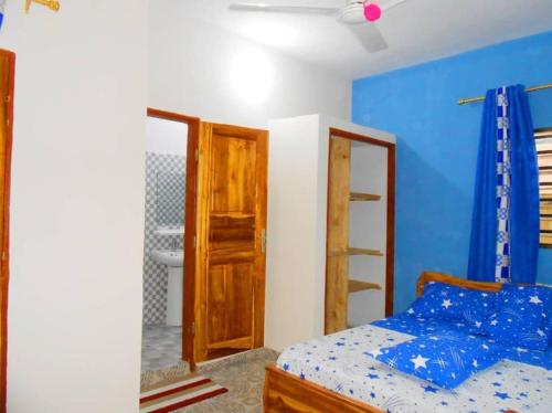 a bedroom with a bed and a blue wall at Maison d'hôte avec paillote in Palimé