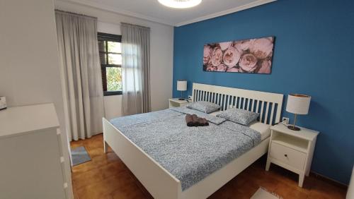 Un dormitorio con una cama con una pared azul. en Spacious apartment with private garden in Tenerife south, en San Miguel de Abona